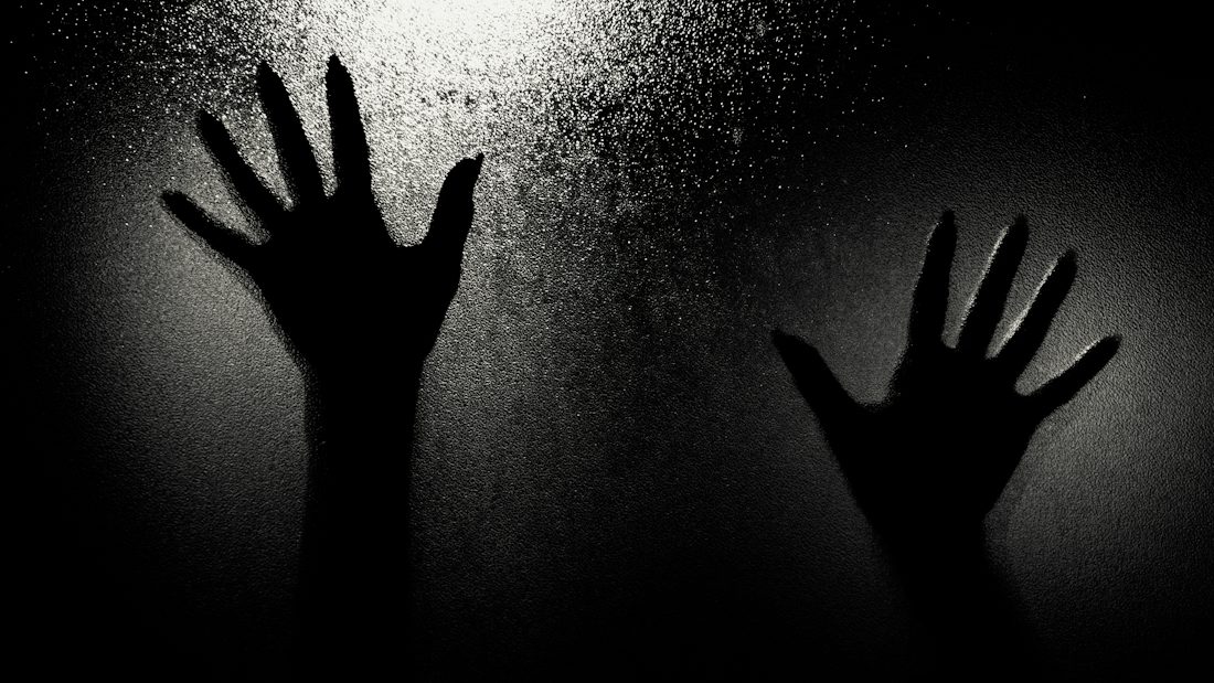 Shadowy hands pressed against frosted glass
